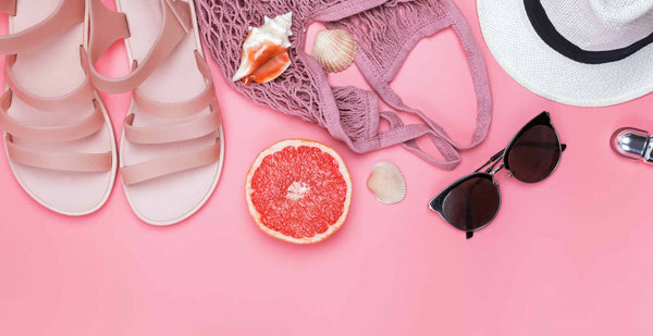 flat lay composition with pastel pink sandals, sunglasses, hat, bag.